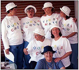 Dore Rotundo sitting in front of six friends wearing sailor caps and tee shirts that say Dore's crew.
