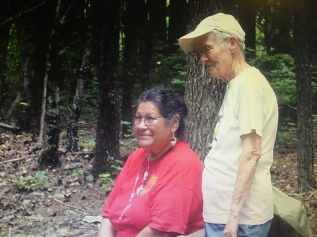 Beverly Little Thunder and Ellen Spangler are in a clearing with trees behind them