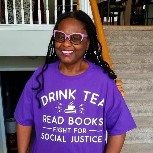 Mary Anne wearing purple tee shirt reading drink tea, read books, fight for social justice