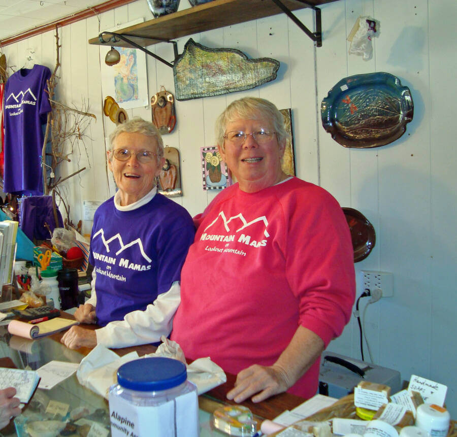 Ellen Spangler and Mary Alice Stout wearing Mountain Mama's sweat shirts standing behind a counter in their store