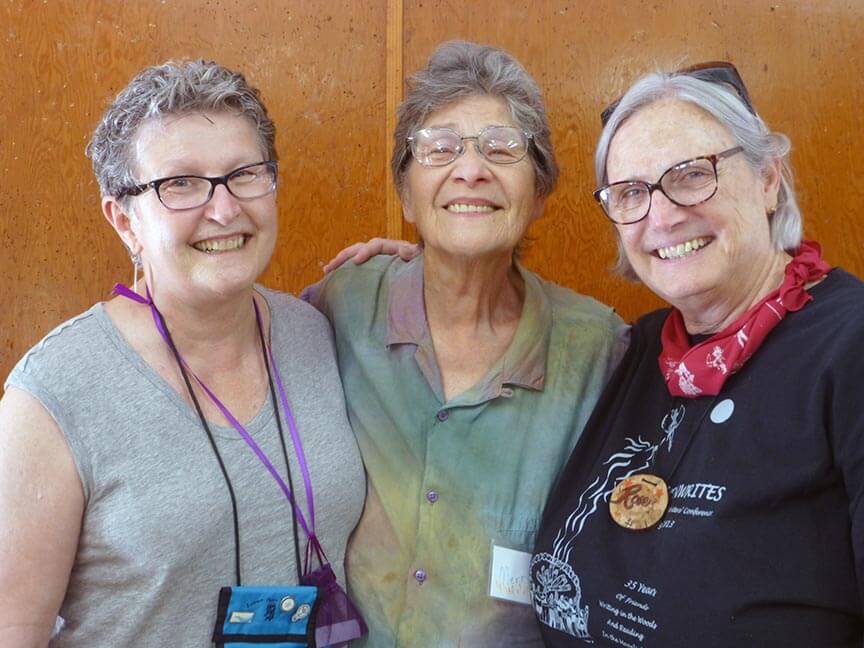 Three smiling women photographed from the waist up.