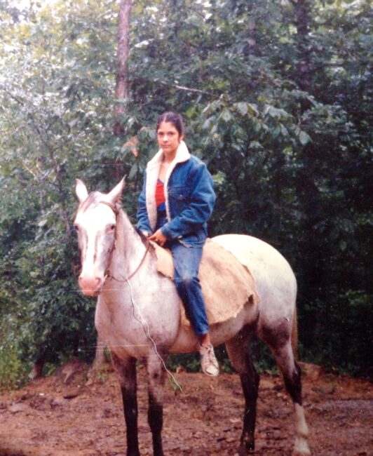 young woman sitting on white horse