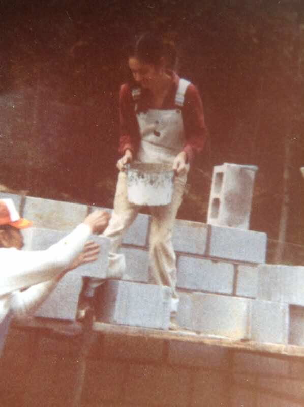 SunHawk holding can of cement while building wall with dad, Jose Morales