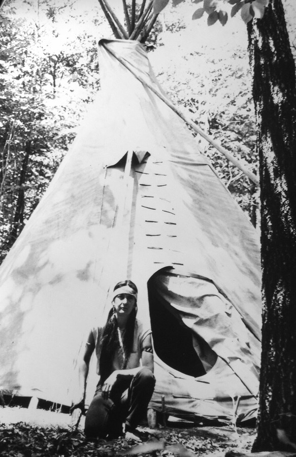 Sun Hawk (Aguila) kneeling in front of tipi she built