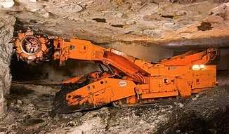 large piece of machinery grinding rock in a tunnel wall