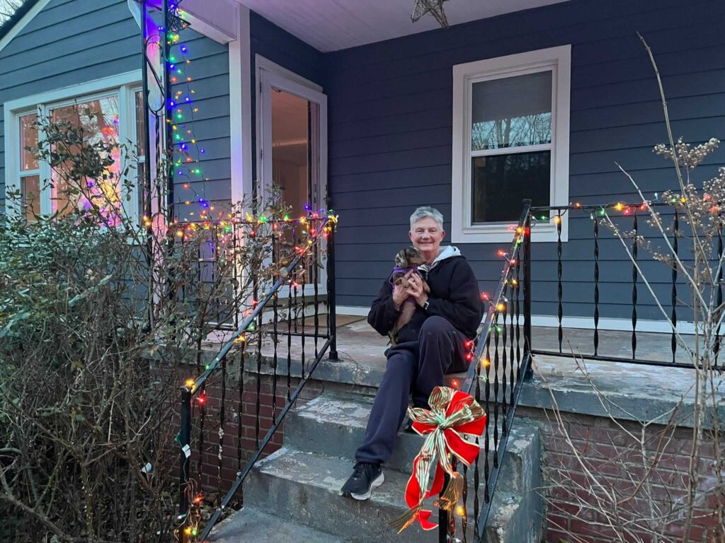 Mendy Knott sitting on her front porch stairs holding her dachshund