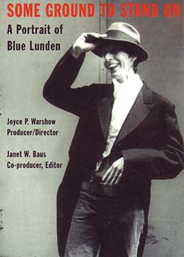Blue Lunden is wearing a tuxedo jacket, jeans, and a fedora hat