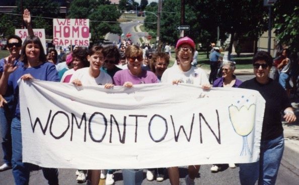 group of women holding a Womontown flag at pride march