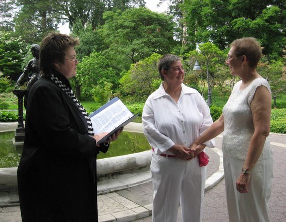 Leaf and Drea at their wedding, standing in front of female minister