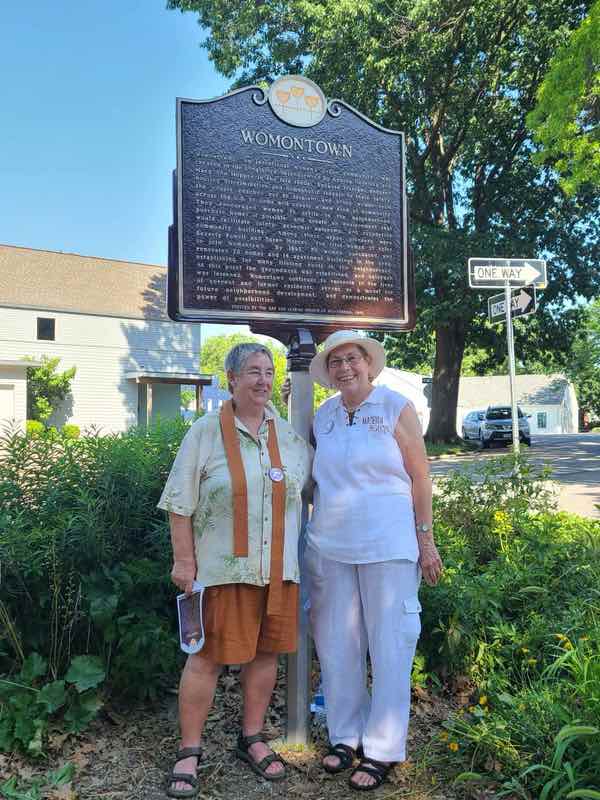 Drea and Leaf standing in front of Womontown plaque
