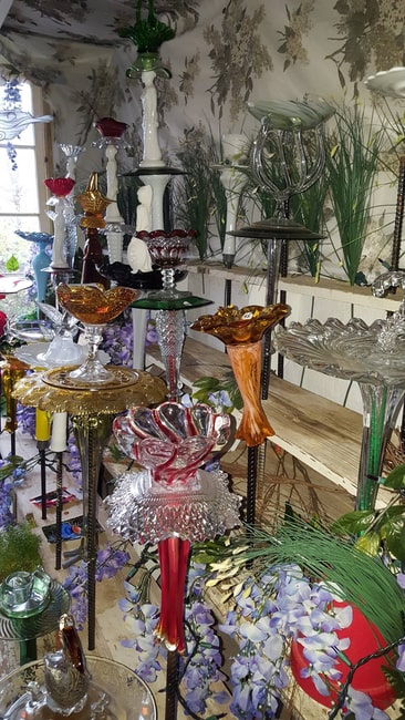 many colorful glass bird baths and sculptures in a shop