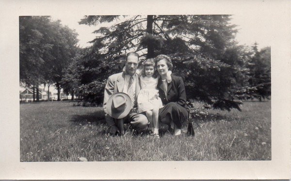 Leaf standing between her with parents in a field