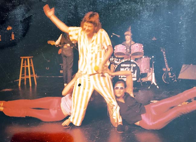 Moral Hazard onstage Jan in striped pajamas flanked by snake dancers
