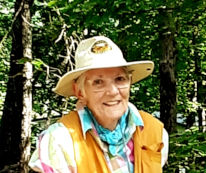 Barbara outdoors dressed for bushwhacking, wearing a wide-brimmed hat