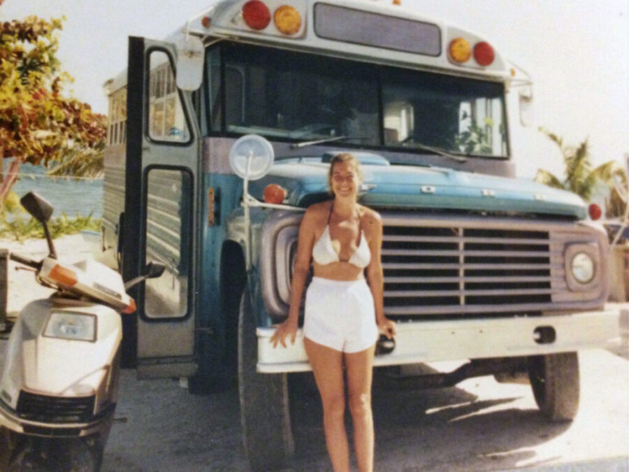 Bonnie stands in front of the grill of a baby blue bus