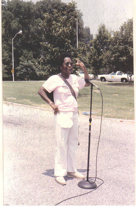 Carolyn Mobley-Bowie standing at a microphone outdoors