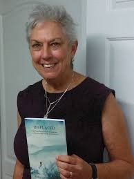 Debra L. Gish holding her book Displaced: A Perilous True Story of an Expatriate Working to Right Wrongs from the Past.