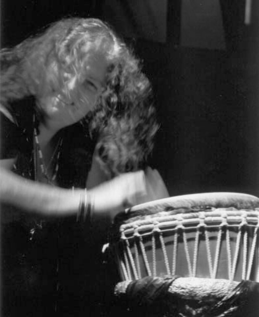 Flash Silvermoon smiling through long wild hair. Drumming hands are a blur of speed.