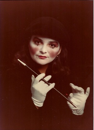 Pici is all in black with a white face and white gloves, holding a black wand.