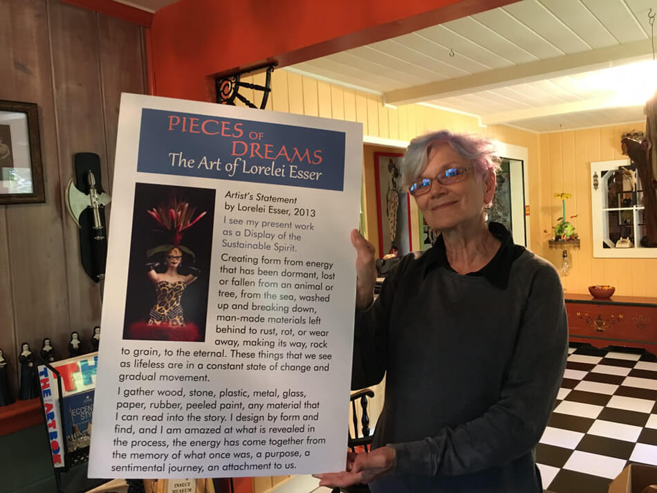 Smiling woman holds a poster titled Pieces of Dreams, the Art of Lorelei Esser