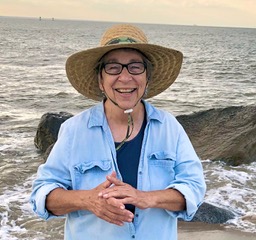 Phylis grinning in sunhat at the ocean