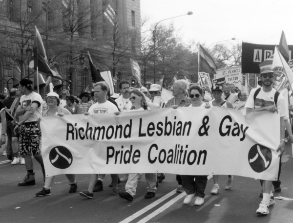 Three women and two men, surrounded by gay pride marchers, proudly carry the Richmond Lesbian and Gay Pride Coalition banner.