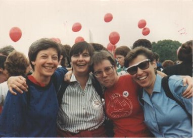 Four young white women, Saralyn Chesnut to the left, arms around shoulders, posing and smiling.