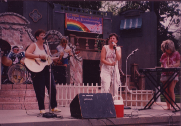 Musicians performing on an outdoor stage in an urban setting.